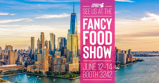 NYC buildings backdrop. the Hungry Squirrel logo. Visit us at the Fancy Food Show, June 12-14, Booth 3242