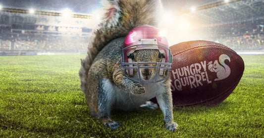 sammie the squirrel on a football field with a Hungry Squirrel football and wearing a helmet