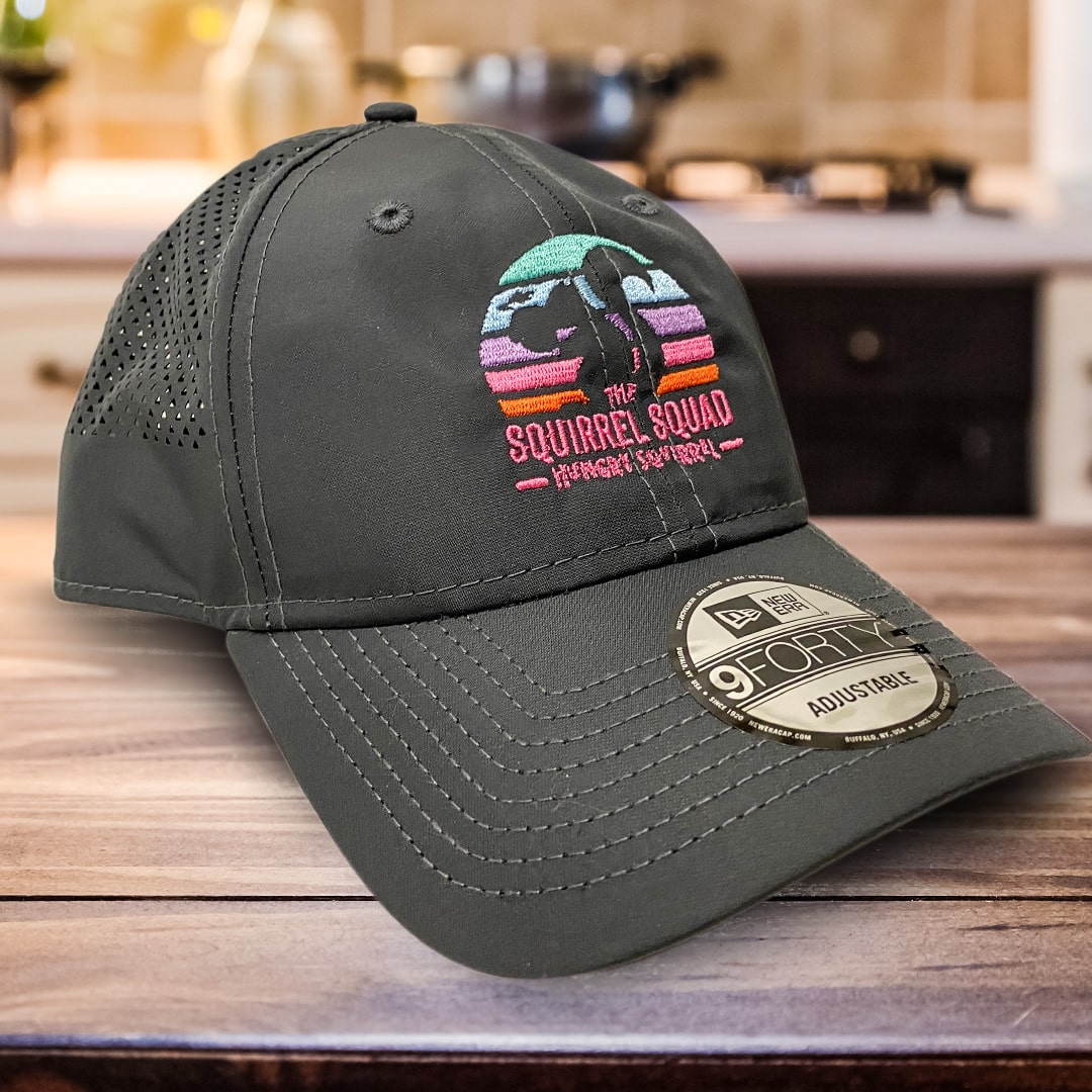 Grey Unisex Squirrel Squad Cap with The Squirrel Squad Logo over a wood counter